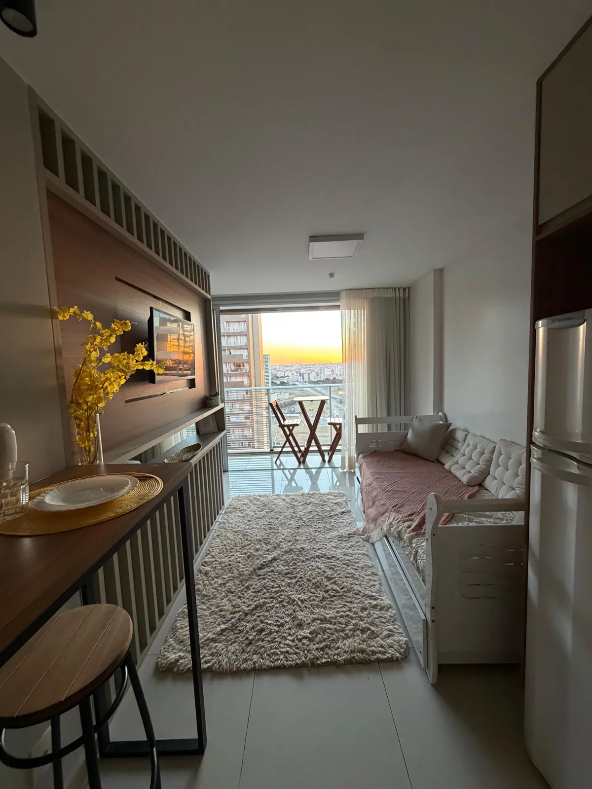 Sala do flat da Bothanic Flats em Brasília, com varanda e pôr do sol